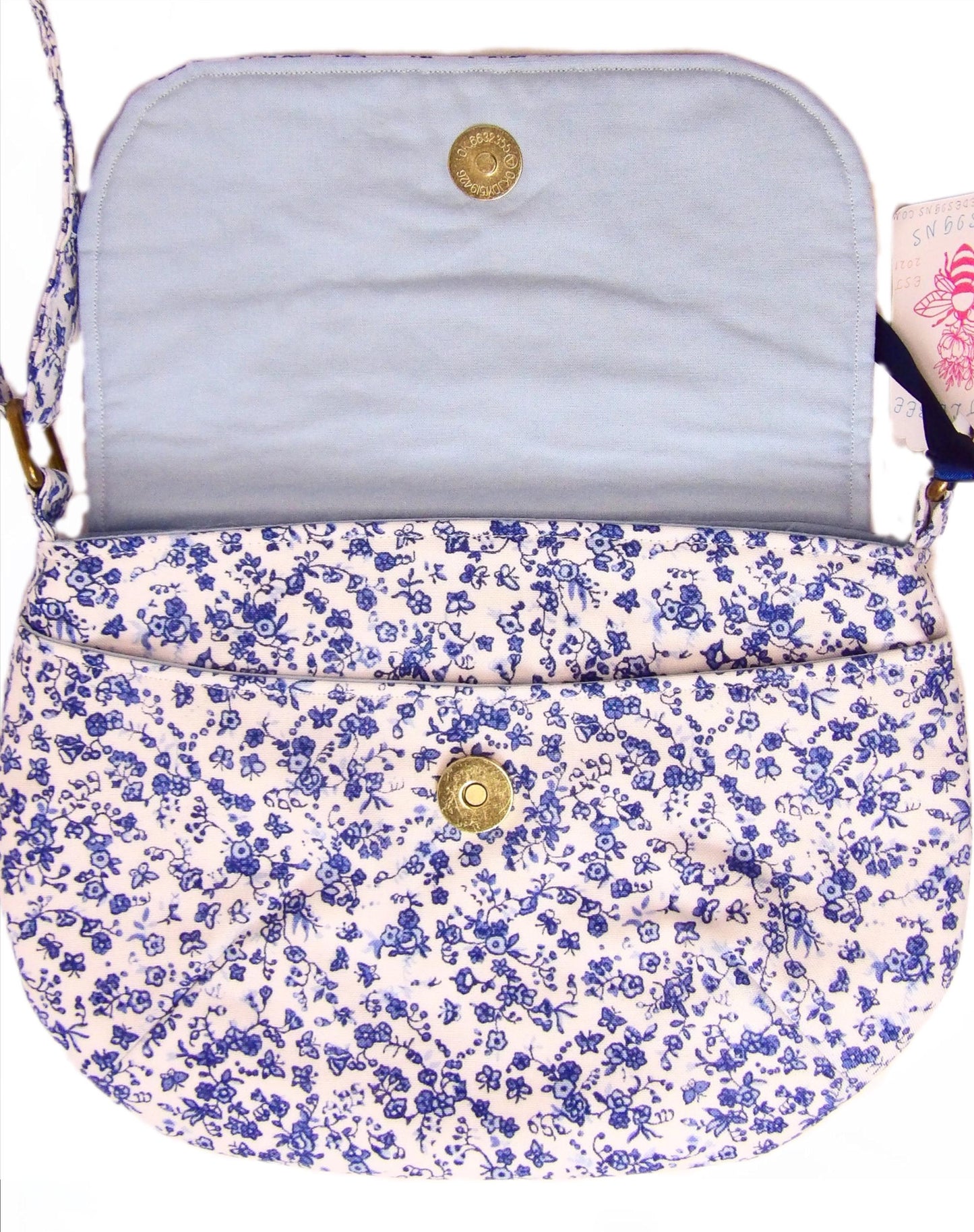 close up of open blue and white floral fabric crossbody bag with whimsical butterfly motifs. Lightweight boho crossbody bag with enchanting flower fabric perfect for festivals and outings