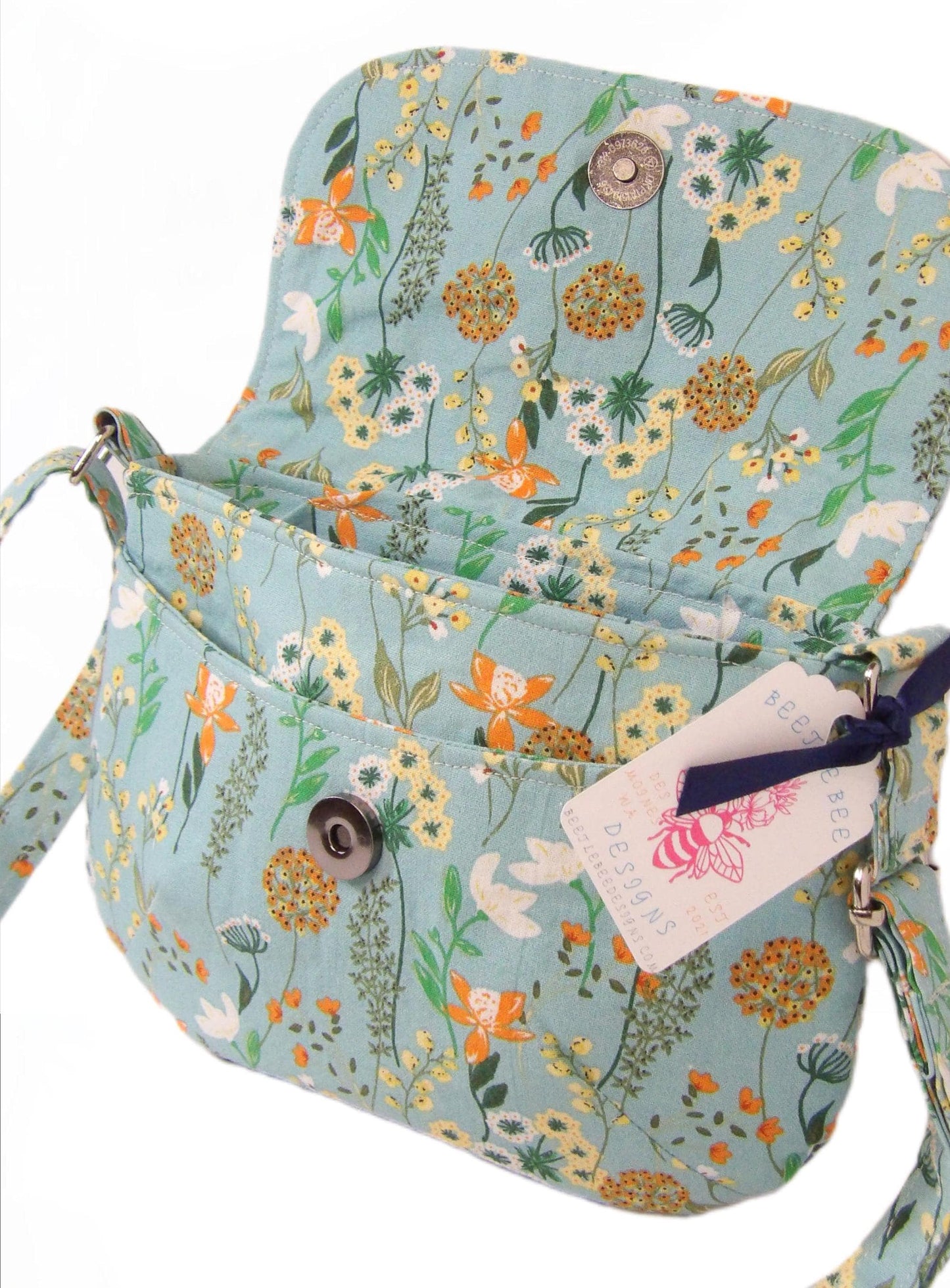 close up of open whimsical floral fabric cotton crossbody purse. Bohemian style can be worn across the body or on the shoulder. Lightweight and perfect for festivals and day trips with adjustable strap and magnetic closure.