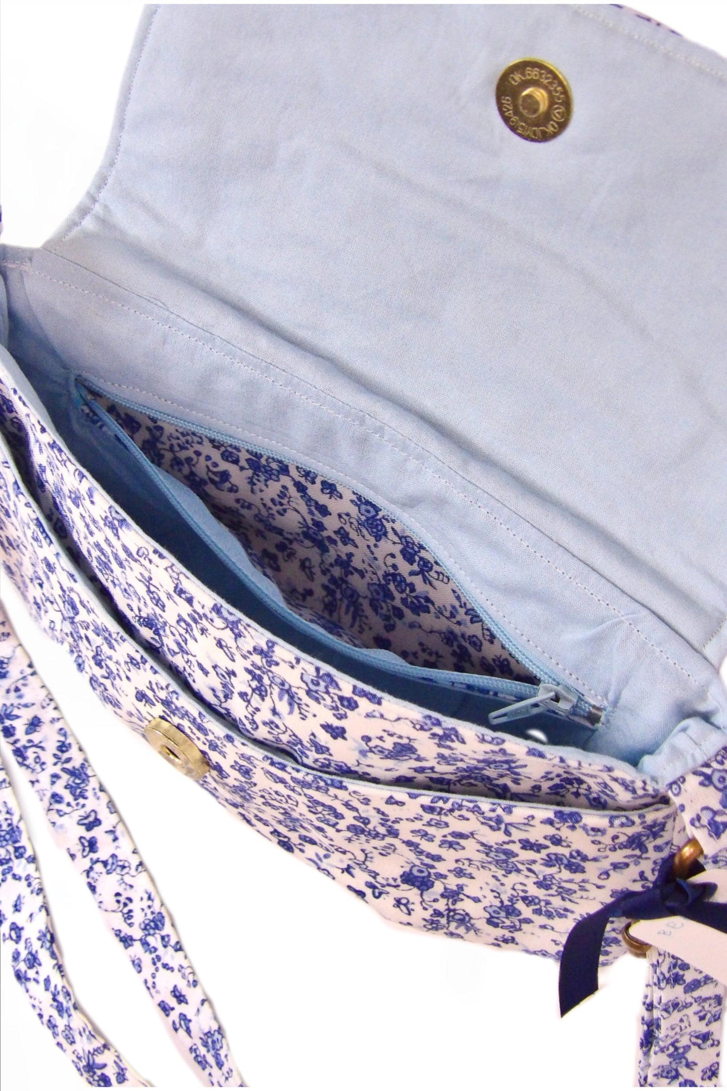 close up of open blue and white floral fabric crossbody bag with whimsical butterfly motifs. Lightweight boho crossbody bag with enchanting flower fabric perfect for festivals and outings
