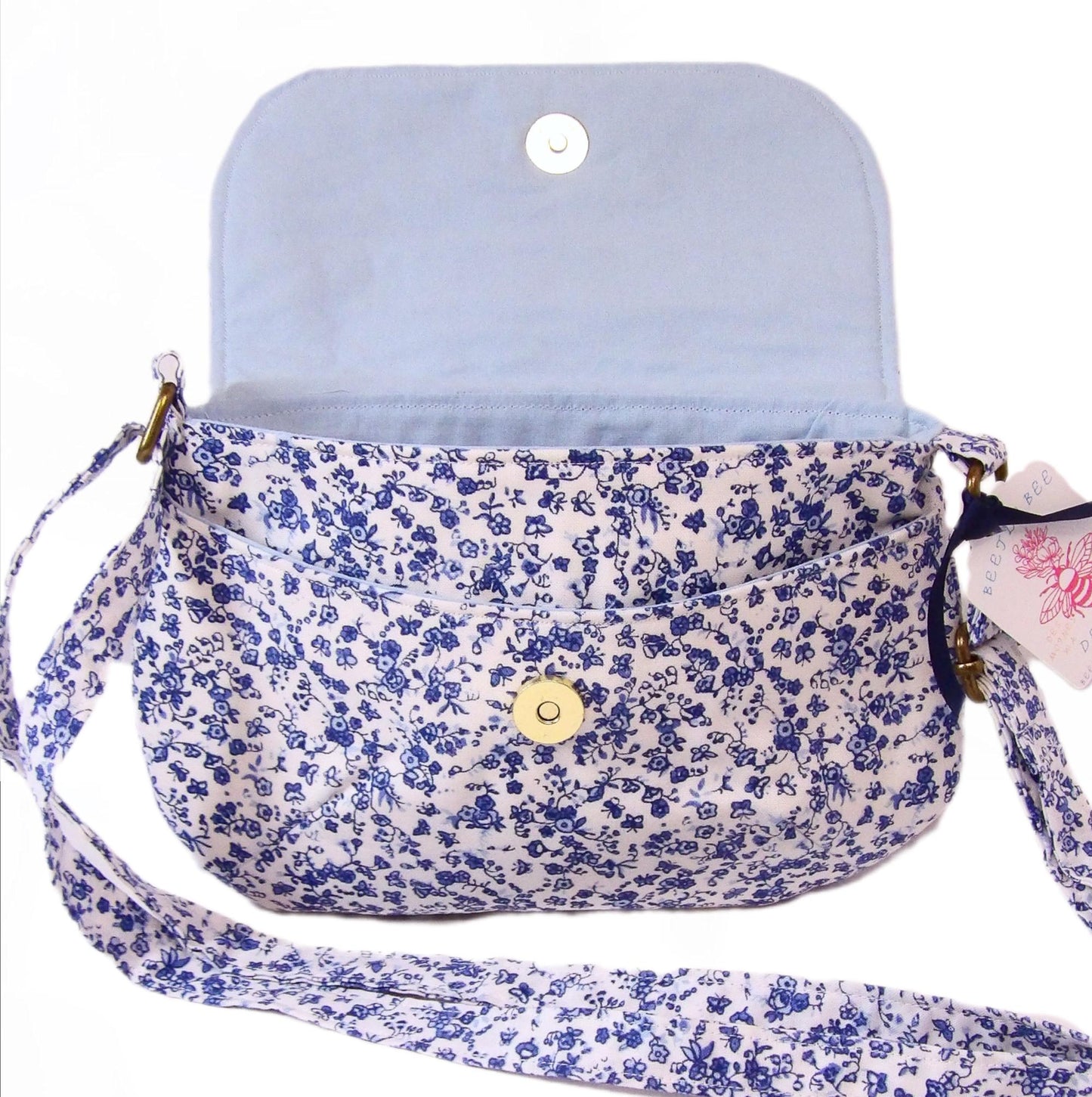 close up of open blue and white floral fabric crossbody bag with whimsical butterfly motifs. Lightweight boho crossbody bag with enchanting flower fabric perfect for festivals and outings