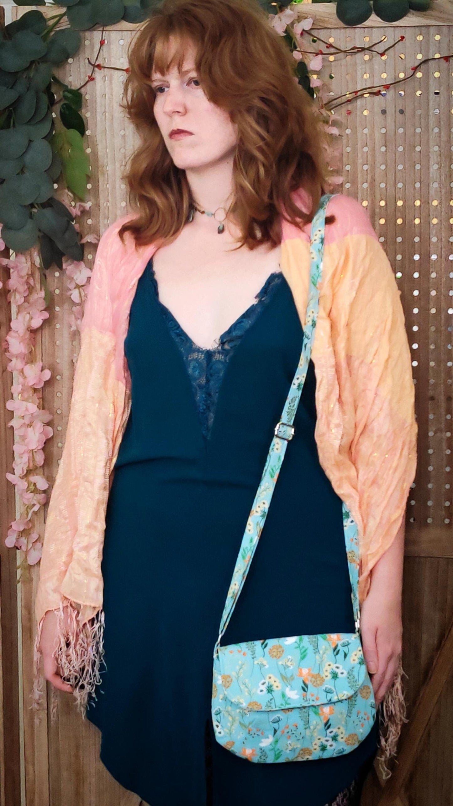 Model wearing whimsical floral fabric cotton crossbody purse. Bohemian style can be worn across the body or on the shoulder. Lightweight and perfect for festivals and day trips with adjustable strap and magnetic closure.