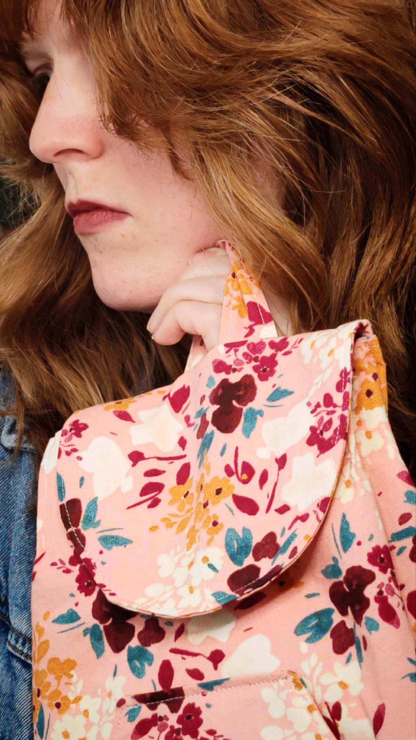 convertible mini backpack purse for women with wildflower cotton fabric. Convertible backpack purse that can be worn as a sling bag. Boho style mini backpack photo of model holding purse by the handle. Bohemian floral fabric