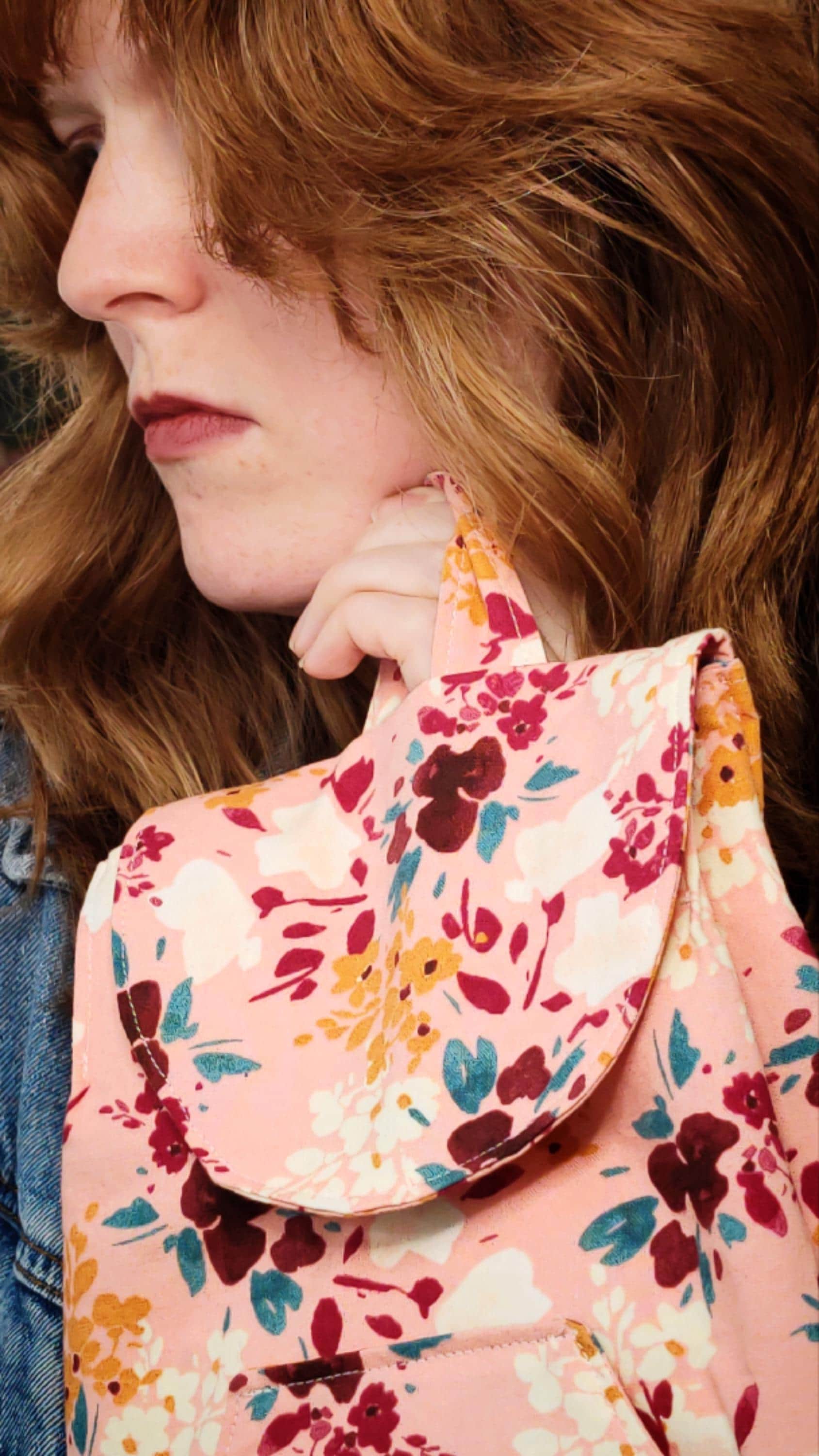 convertible mini backpack purse for women with wildflower cotton fabric. Convertible backpack purse that can be worn as a sling bag. Boho style mini backpack photo of model holding purse by the handle. Bohemian floral fabric