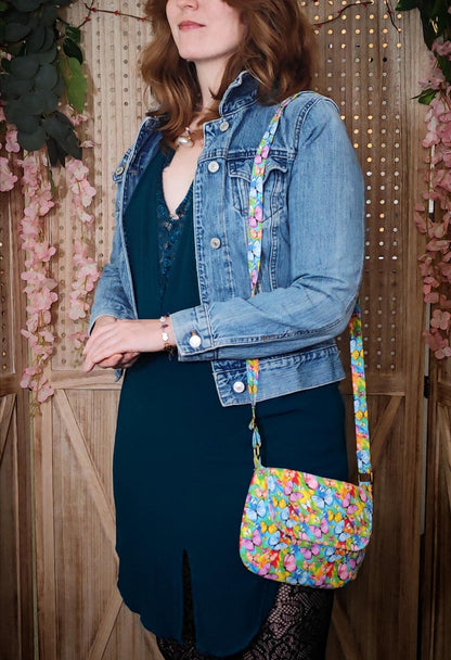 model wearing crossbody fabric purse with colorful rainbow butterfly design perfect for festivals or day trips. Model wearing lightweight crossbody bag with rainbow butterfly fabric in a bohemian style