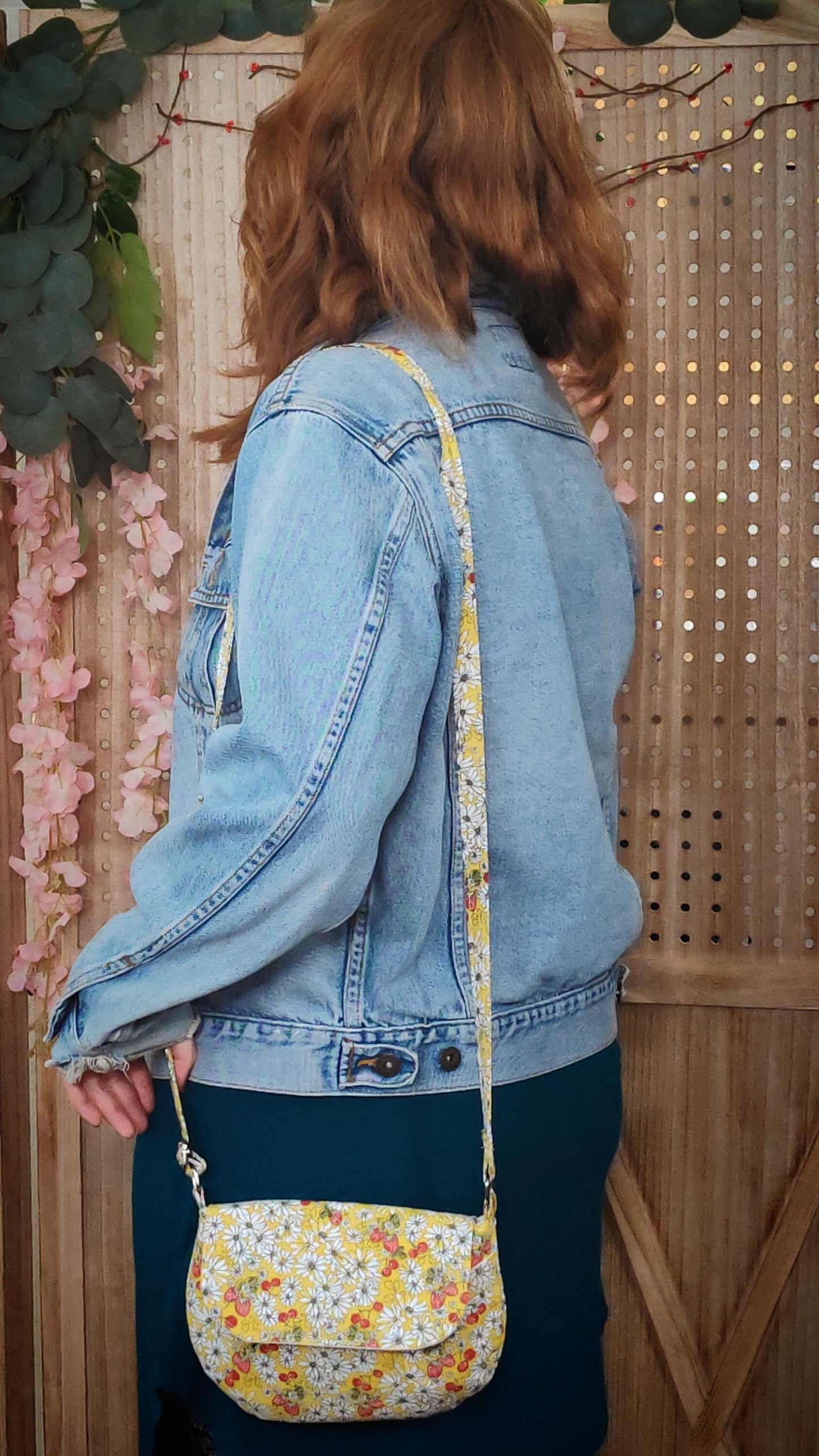 model wearing a daisy fabric crossbody bag with bohemian style cherries and strawberries, lightweight crossbody purse with a whimsical floral print. Cotton fabric boho bag perfect for festivals and outdoor adventures