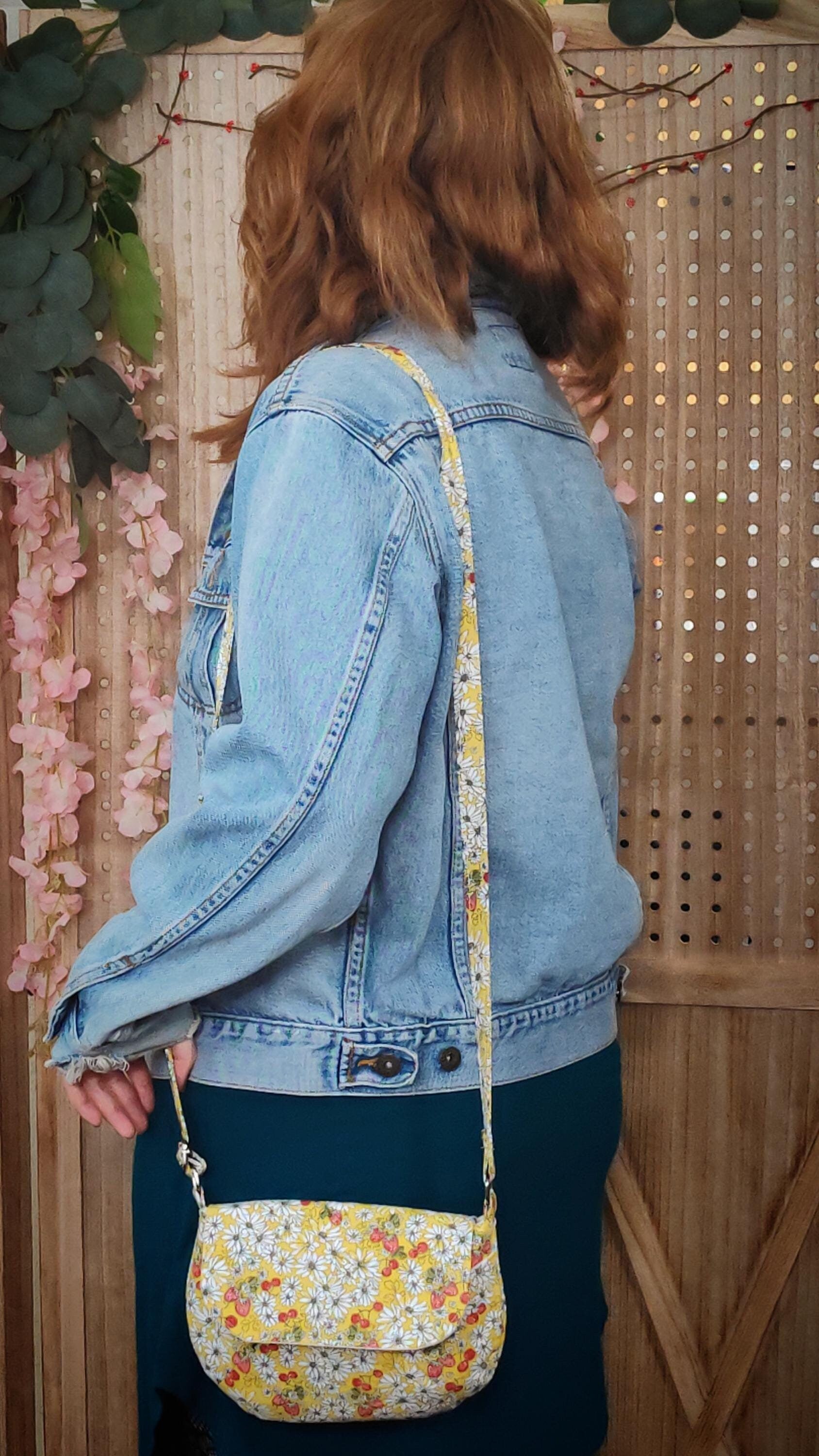 model wearing a daisy fabric crossbody bag with bohemian style cherries and strawberries, lightweight crossbody purse with a whimsical floral print. Cotton fabric boho bag perfect for festivals and outdoor adventures