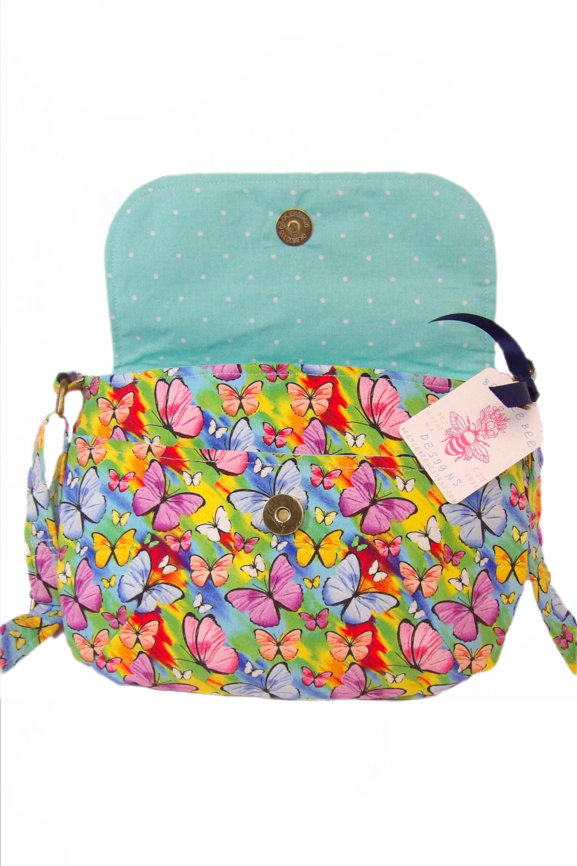 Open view of crossbody fabric purse with colorful rainbow butterfly design perfect for festivals or day trips. Model wearing lightweight crossbody bag with rainbow butterfly fabric in a bohemian style