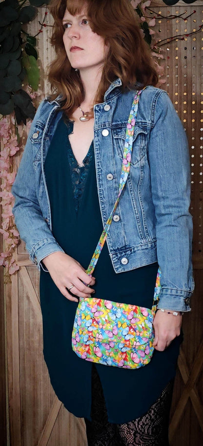 crossbody fabric purse with colorful rainbow butterfly design perfect for festivals or day trips. Model wearing lightweight crossbody bag with rainbow butterfly fabric in a bohemian style