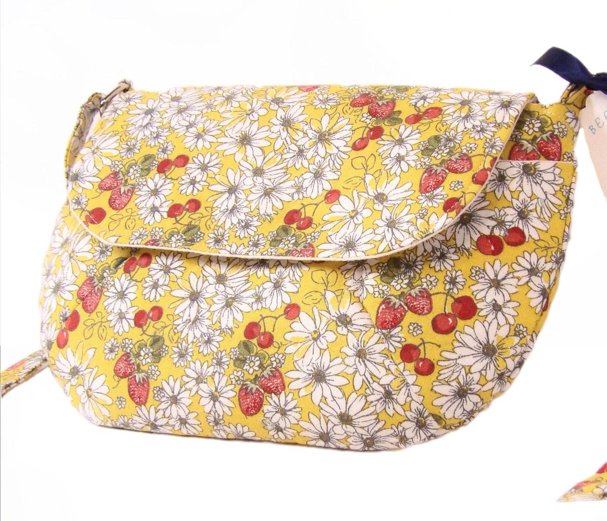 close up side view of a closed daisy fabric crossbody bag with bohemian style cherries and strawberries, lightweight crossbody purse with a whimsical floral print. Cotton fabric boho bag perfect for festivals and outdoor adventures
