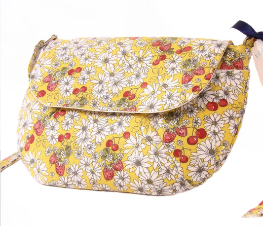 close up side view of a closed daisy fabric crossbody bag with bohemian style cherries and strawberries, lightweight crossbody purse with a whimsical floral print. Cotton fabric boho bag perfect for festivals and outdoor adventures