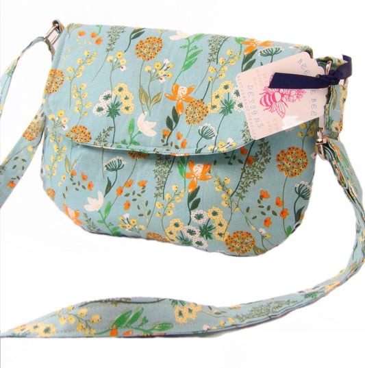 close up of whimsical floral fabric cotton crossbody purse. Bohemian style can be worn across the body or on the shoulder. Lightweight and perfect for festivals and day trips with adjustable strap and magnetic closure.