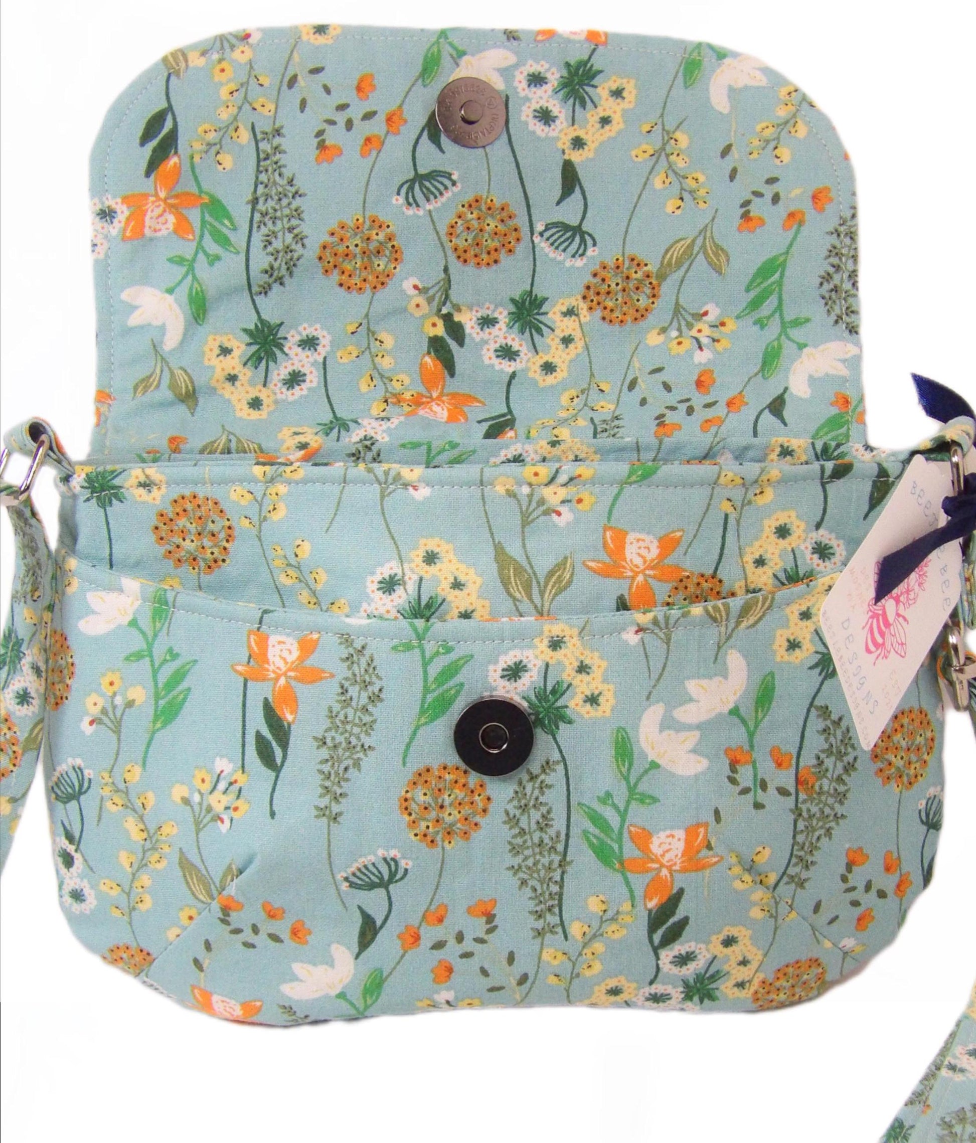 close up of open whimsical floral fabric cotton crossbody purse. Bohemian style can be worn across the body or on the shoulder. Lightweight and perfect for festivals and day trips with adjustable strap and magnetic closure.