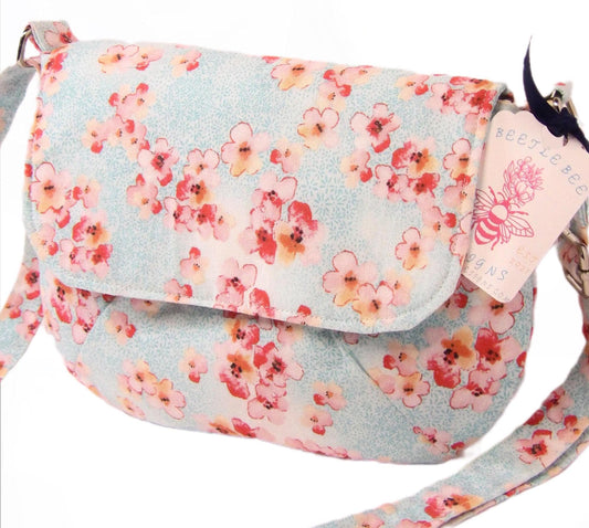 cherry blossoms on blue fabric lightweight boho style crossbody bag. Purse has magnetic closure and adjustable strap for wear on shoulder or across the body. Lightweight and bohemian flare perfect for festivals