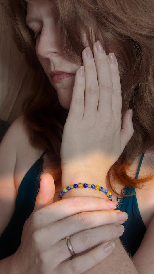 millefiori glass bead bracelet with alternating blue and yellow pattern being worn on model in a bohemian style.