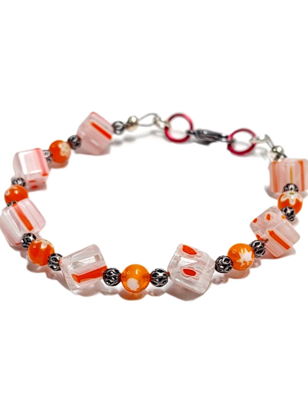 millefiori glass beaded bracelet made with floral mosaic beads and lace style rounds in a bohemian style. Colors are orange, white and grey.