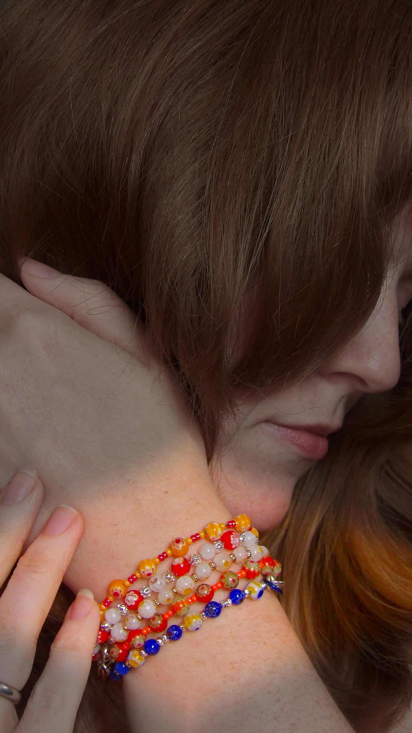 model wearing millefiori mosaic beaded bracelet stack with multicolor floral glass beads in bohemian style . Handmade in the USA