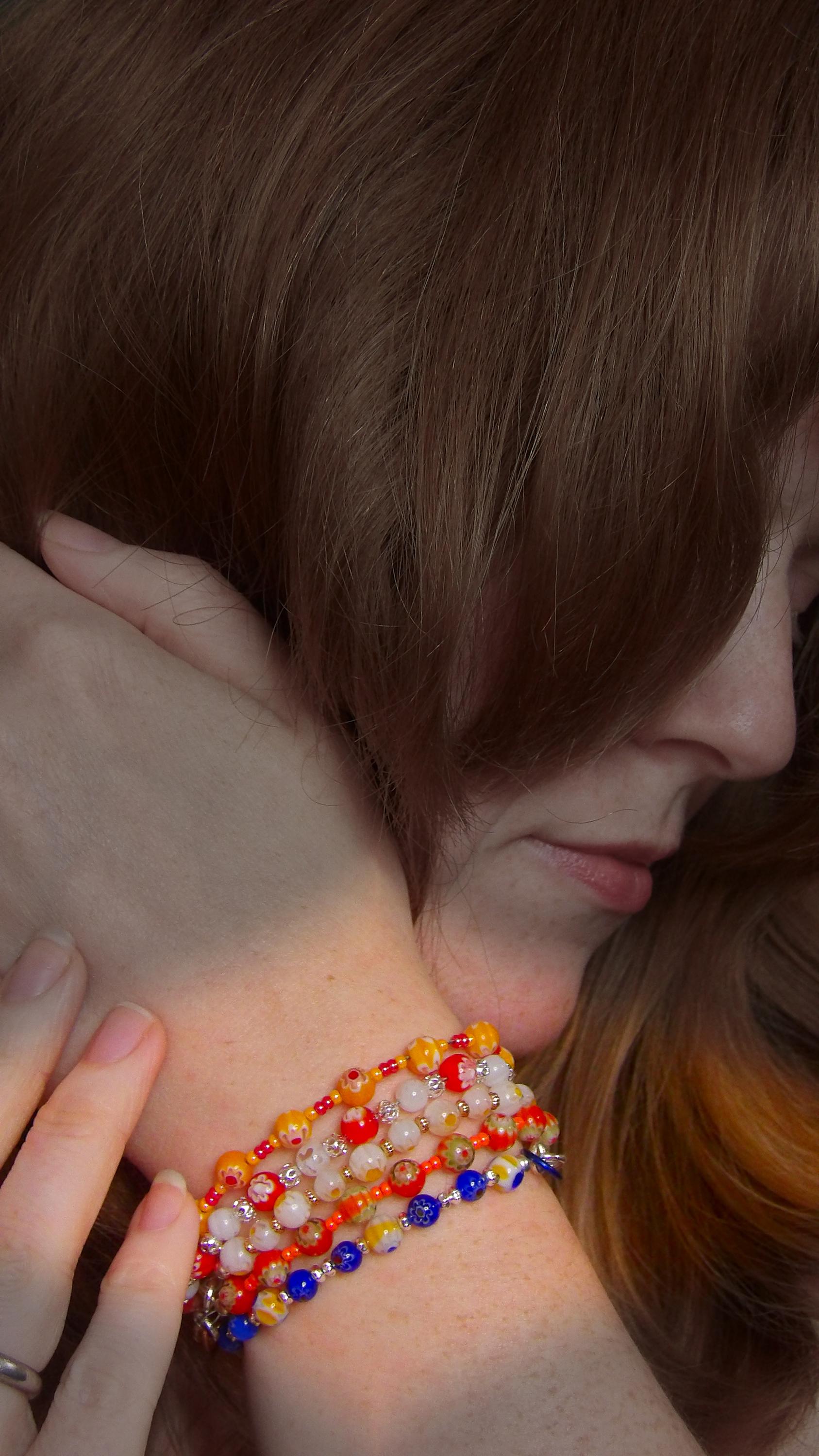 model wearing millefiori mosaic beaded bracelet stack with multicolor floral glass beads in bohemian style . Handmade in the USA