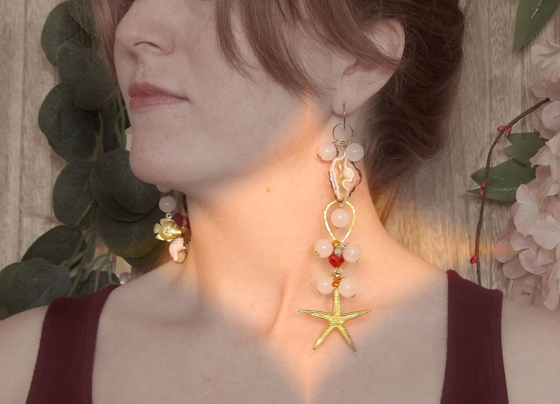Model wearing asymmetrical earrings with ocean sea life charms, agate slices, white jade, amazonite, carnelian and brass findings. Hand made in USA with ethical gemstones in a boho fashion
