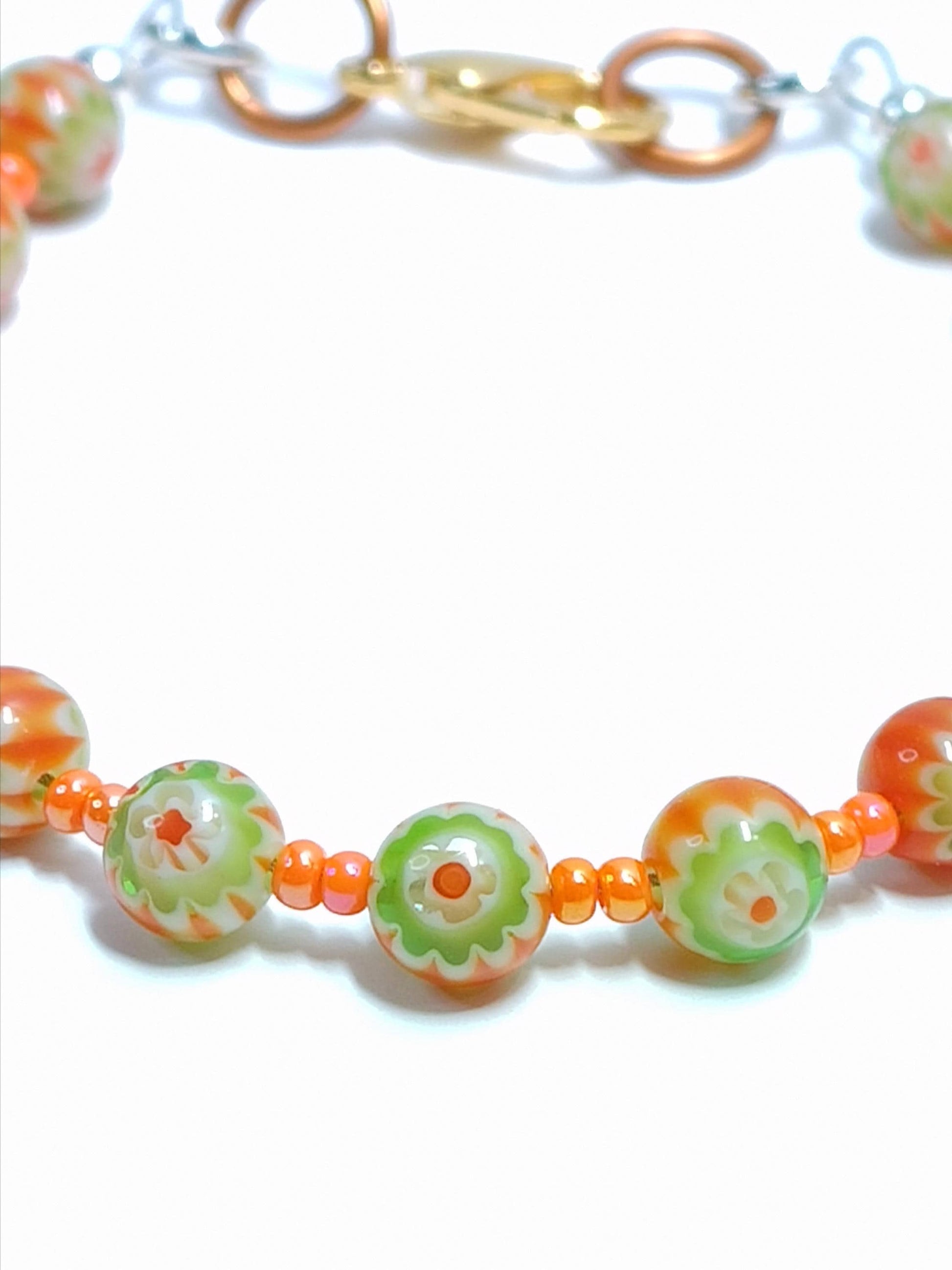 closeup of orange and green millefiori glass beaded bracelet in bohemian style accented by orange czech glass seed beads
