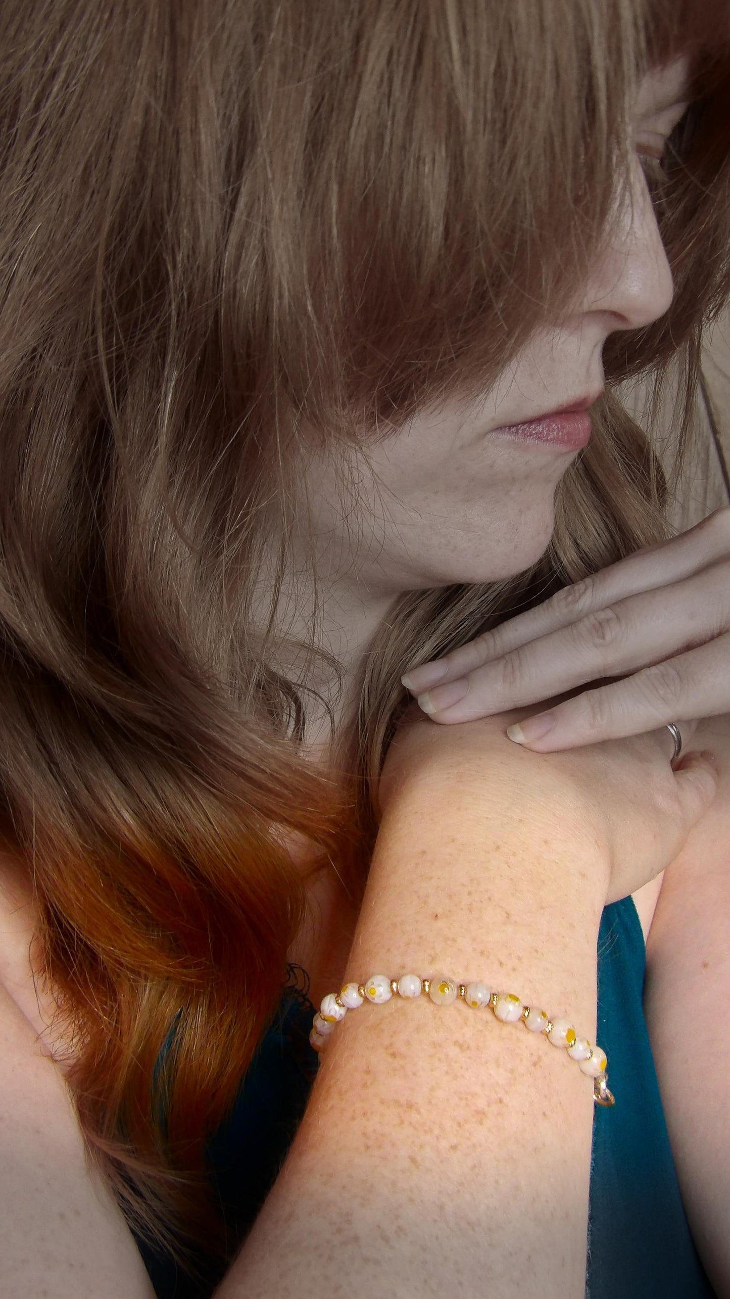 model wearing millefiori mosaic beaded bracelet with white and yellow floral glass beads in bohemian style . Handmade in the USA