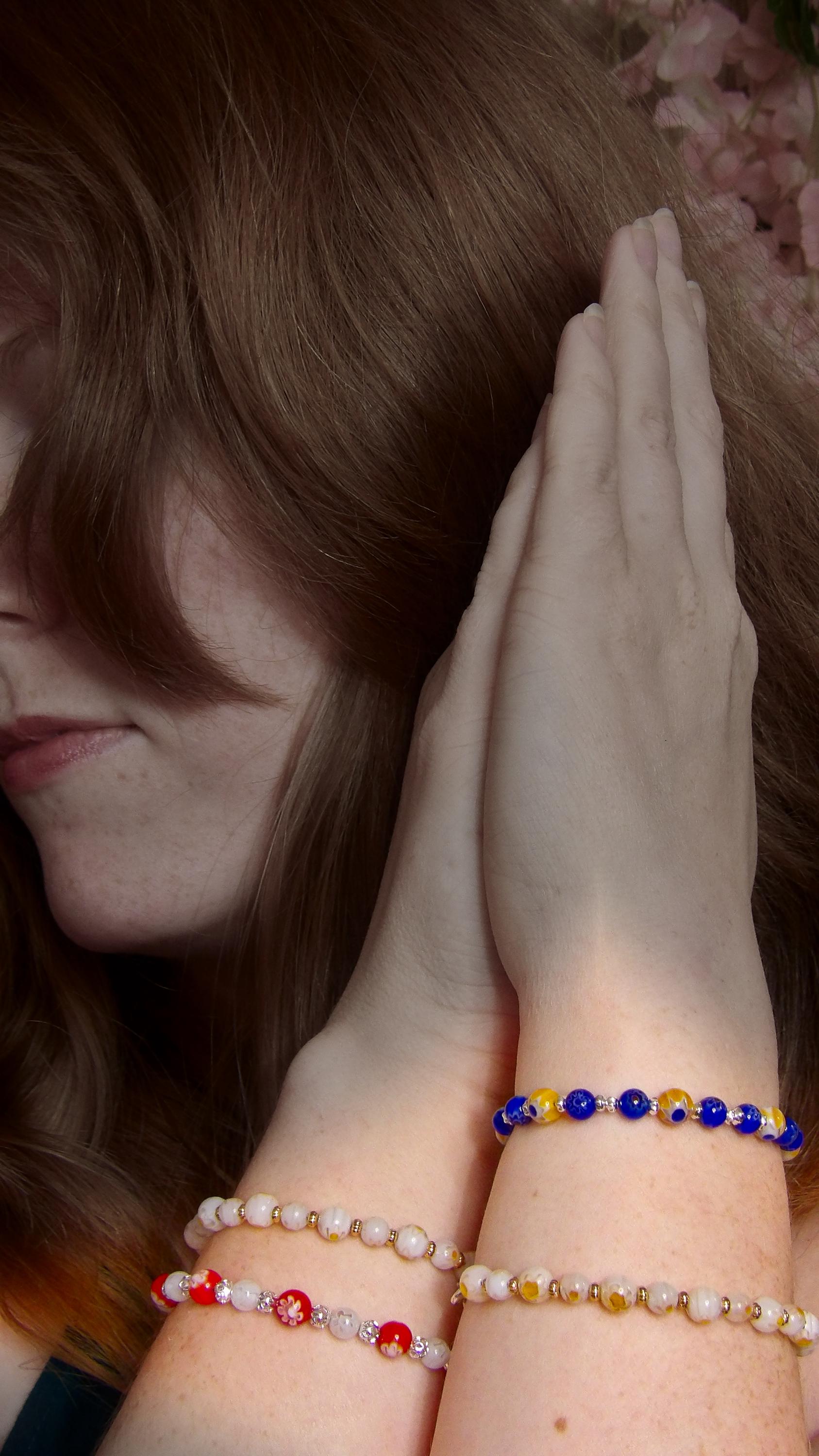 model wearing millefiori mosaic beaded bracelet stack with multicolor floral glass beads in bohemian style . Handmade in the USA