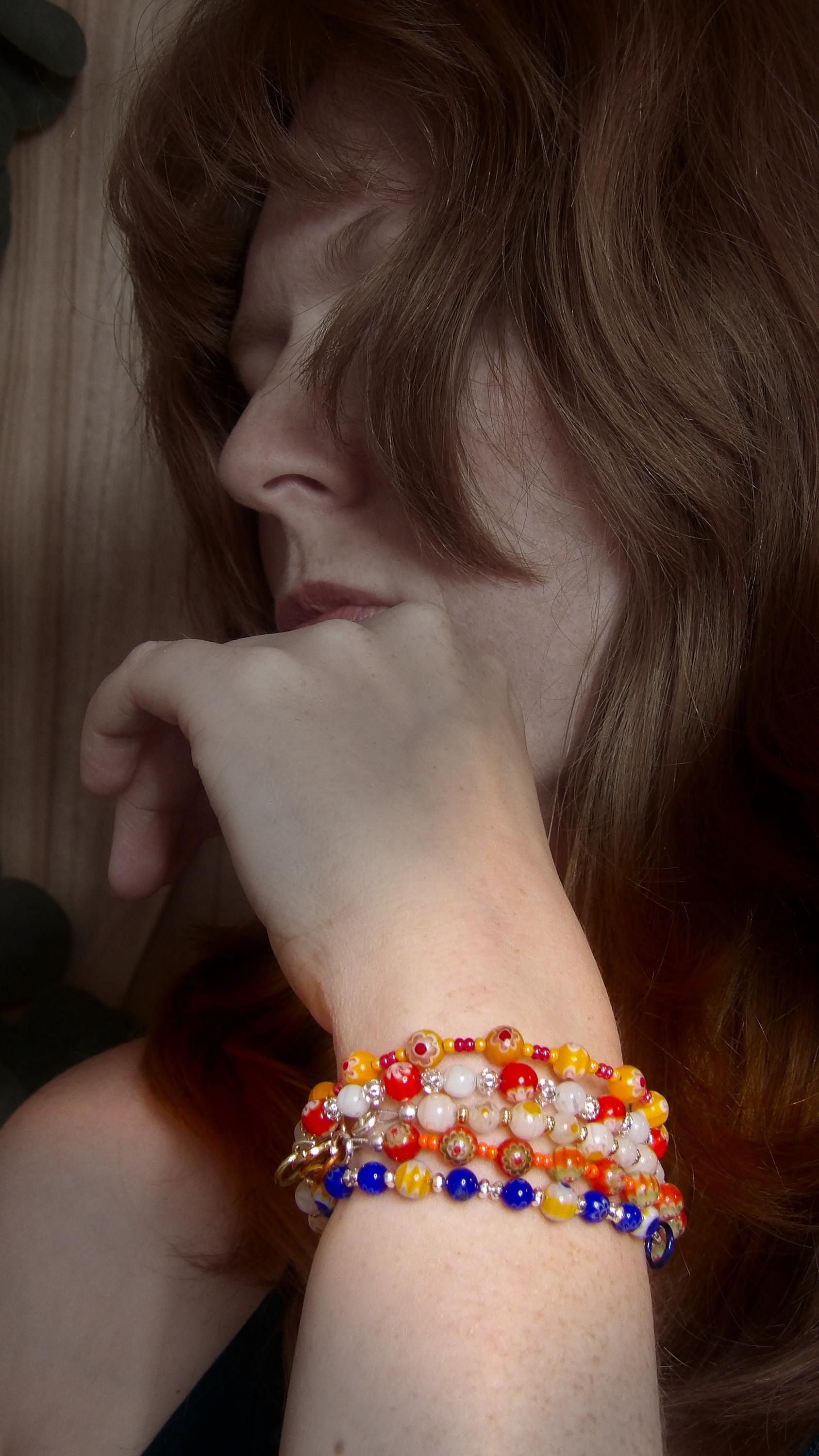 model wearing millefiori mosaic beaded bracelet stack with multicolor floral glass beads in bohemian style . Handmade in the USA