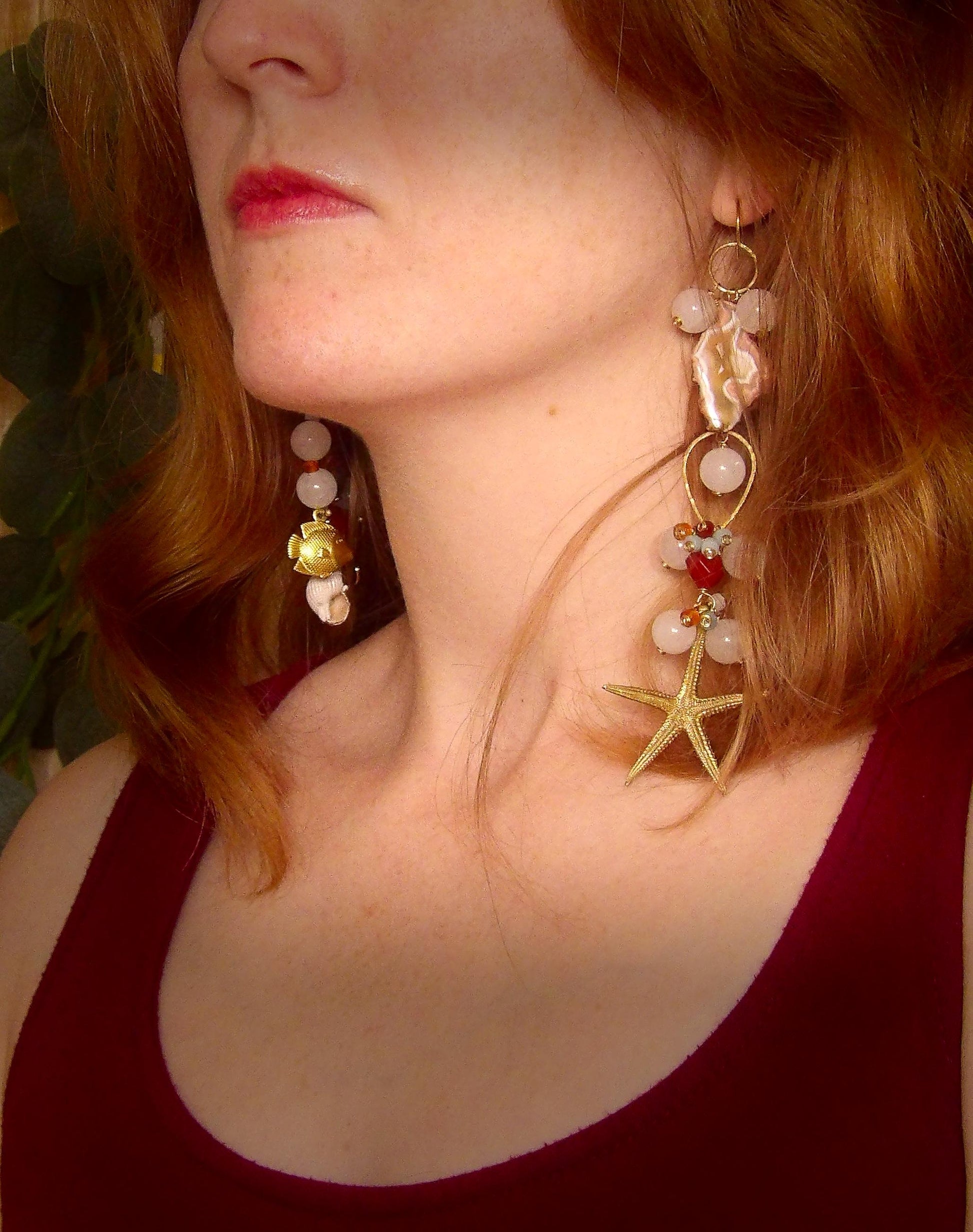 Model wearing asymmetrical earrings with ocean sea life charms, agate slices, white jade, amazonite, carnelian and brass findings. Hand made in USA with ethical gemstones in a boho fashion