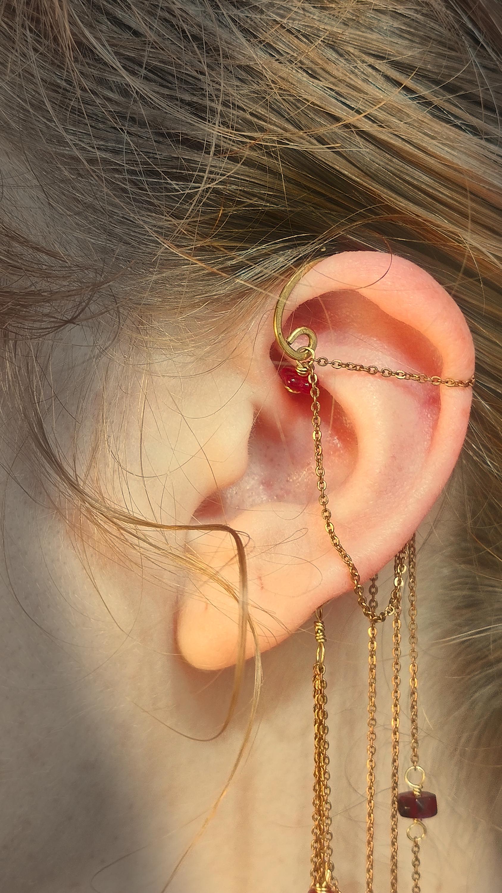 Flower Ear Cuff wrap around earring with red czech glass seed beads. Ear wrap frame sits behind the ear and has chain accents that adorn the top half of the ear along with cascading chains that come from behind the ear. Chains are adorned with hand wrapped czech glass beads in rich red tones. Beads include grape and flower motifs for a rustic, bohemian aura