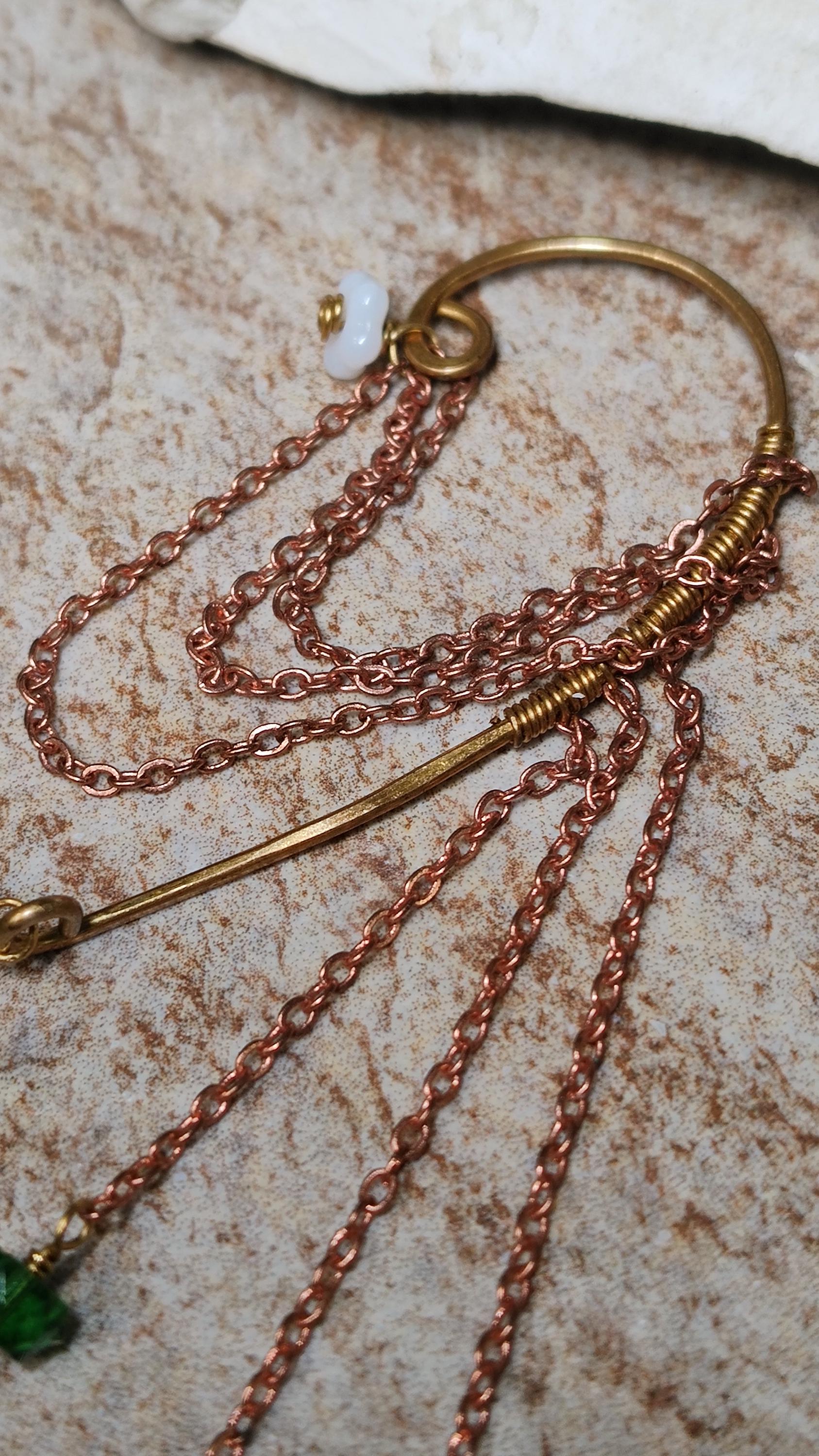 Cottagecore wrap around earring with czech glass flowers and grape beads in shades of green and white. Pierceless design rests behind the ear on a hand forged raw brass frame. Bright copper chains cascade across the top of the ear and from behind the frame for an old world, romantic and rustic vibe. Czech glass beads are hand wrapped and adorned on the the chains throughout the piece