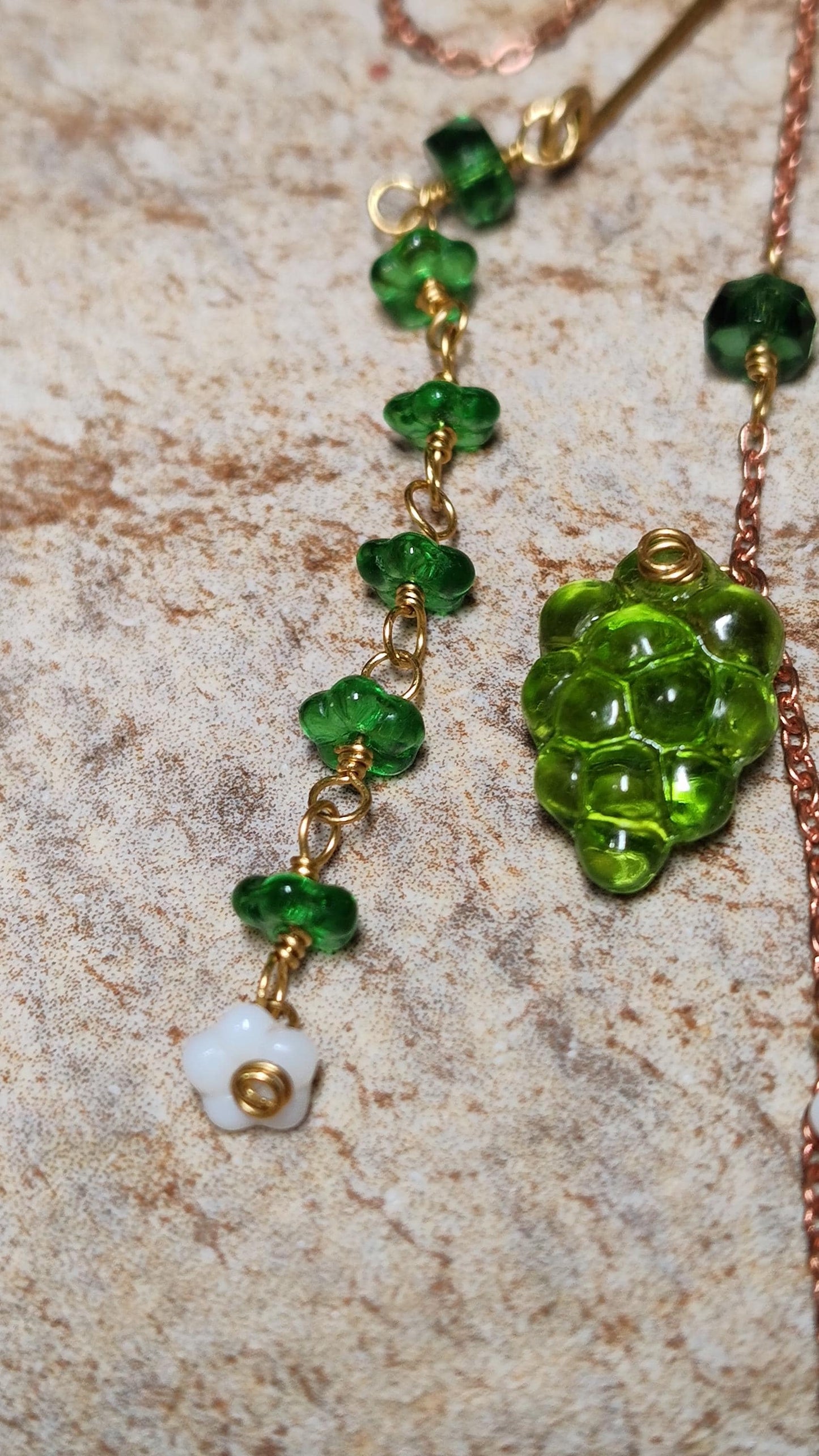 Cottagecore wrap around earring with czech glass flowers and grape beads in shades of green and white. Pierceless design rests behind the ear on a hand forged raw brass frame. Bright copper chains cascade across the top of the ear and from behind the frame for an old world, romantic and rustic vibe. Czech glass beads are hand wrapped and adorned on the the chains throughout the piece